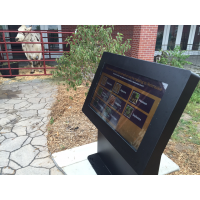 Un chiosco touch screen all'aperto con una mucca sullo sfondo