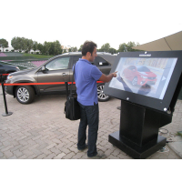 Een man die een buitenkiosk gebruikt met een dik glazen aanraakscherm